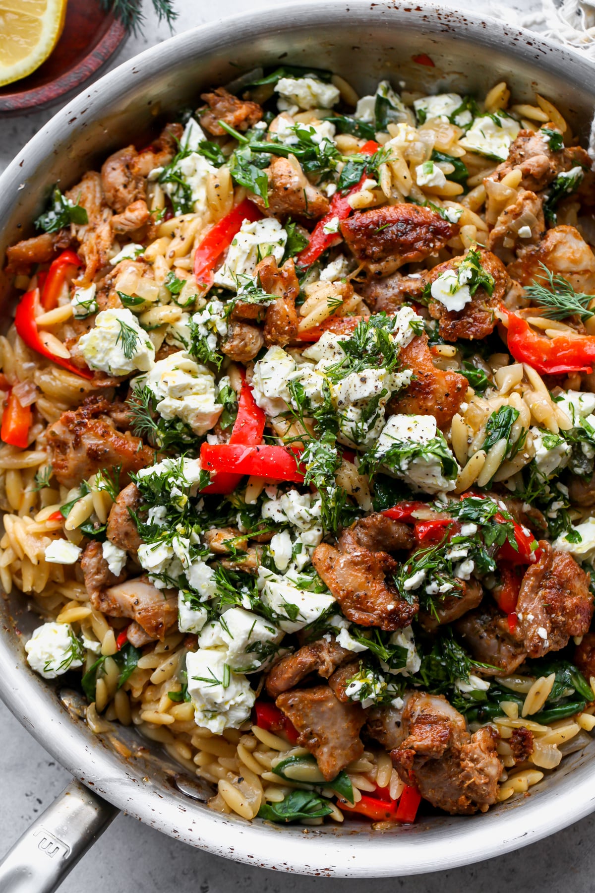 Lemon-Feta Chicken and Orzo in a skillet topped with an herby marinated feta mixture.