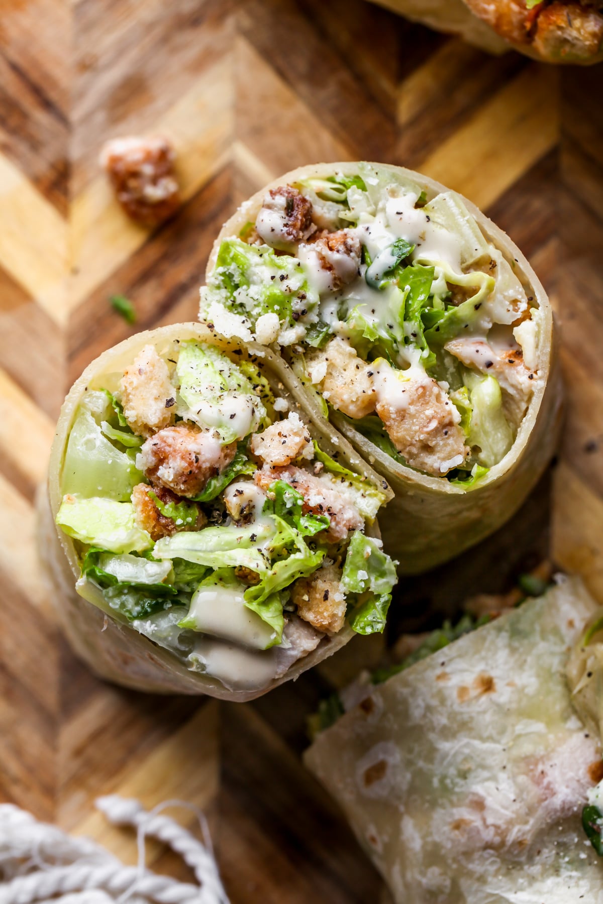 Miso Chicken Caesar Wraps sliced in half on a cutting board to show inside filling.