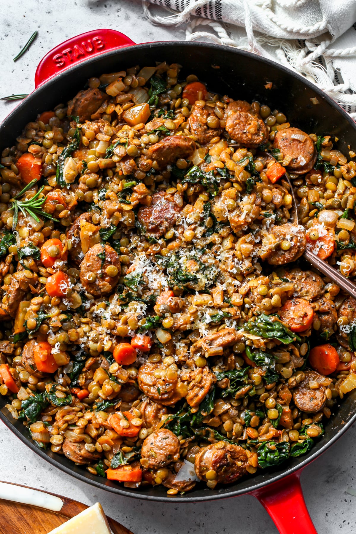 Tuscan sausage and lentils in a cast iron skillet topped with grated cheese.