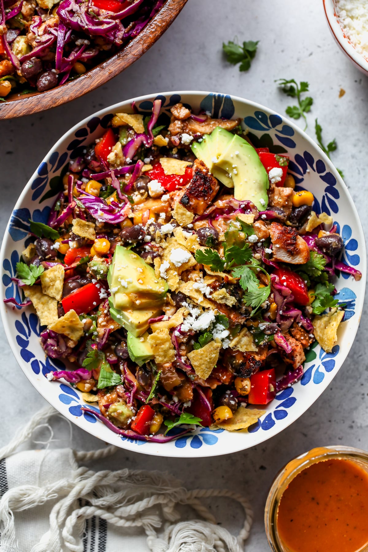 Chipotle chicken salad styled in a white and blue bowl topped with crushed tortilla chips.