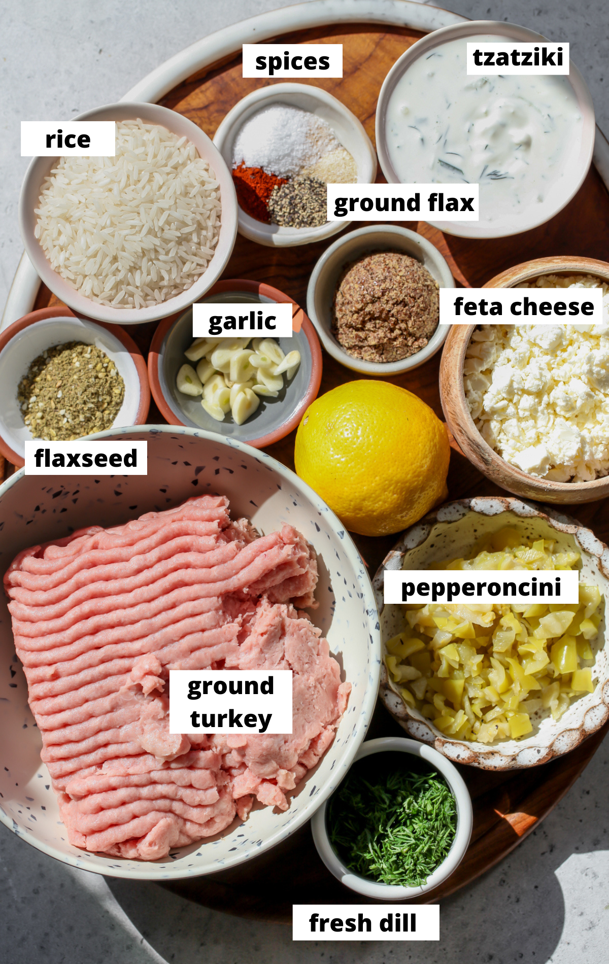 Recipe ingredients in separate bowls arranged on a wooden platter with labels.