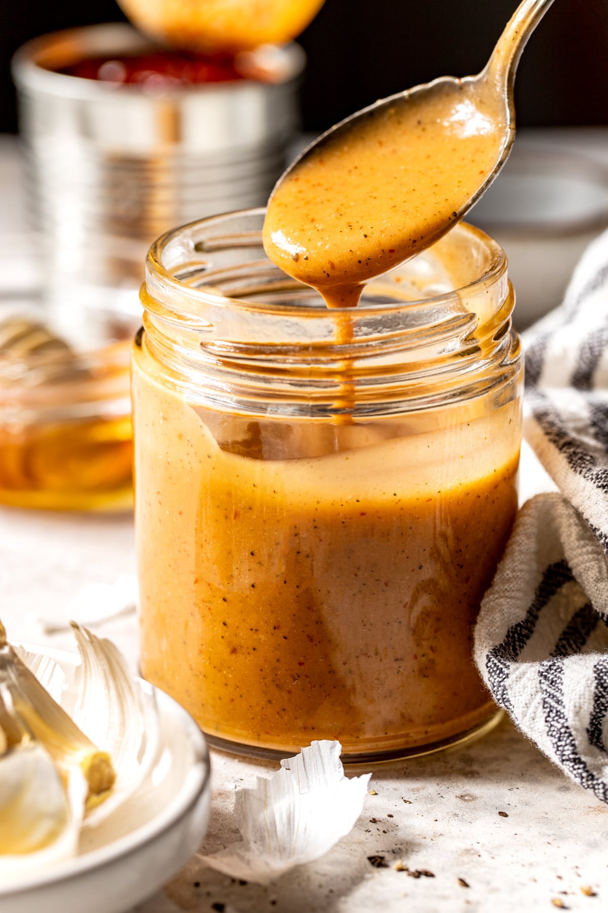 Chipotle vinaigrette in a glass jar with a spoon drizzling a small amount out of the top.