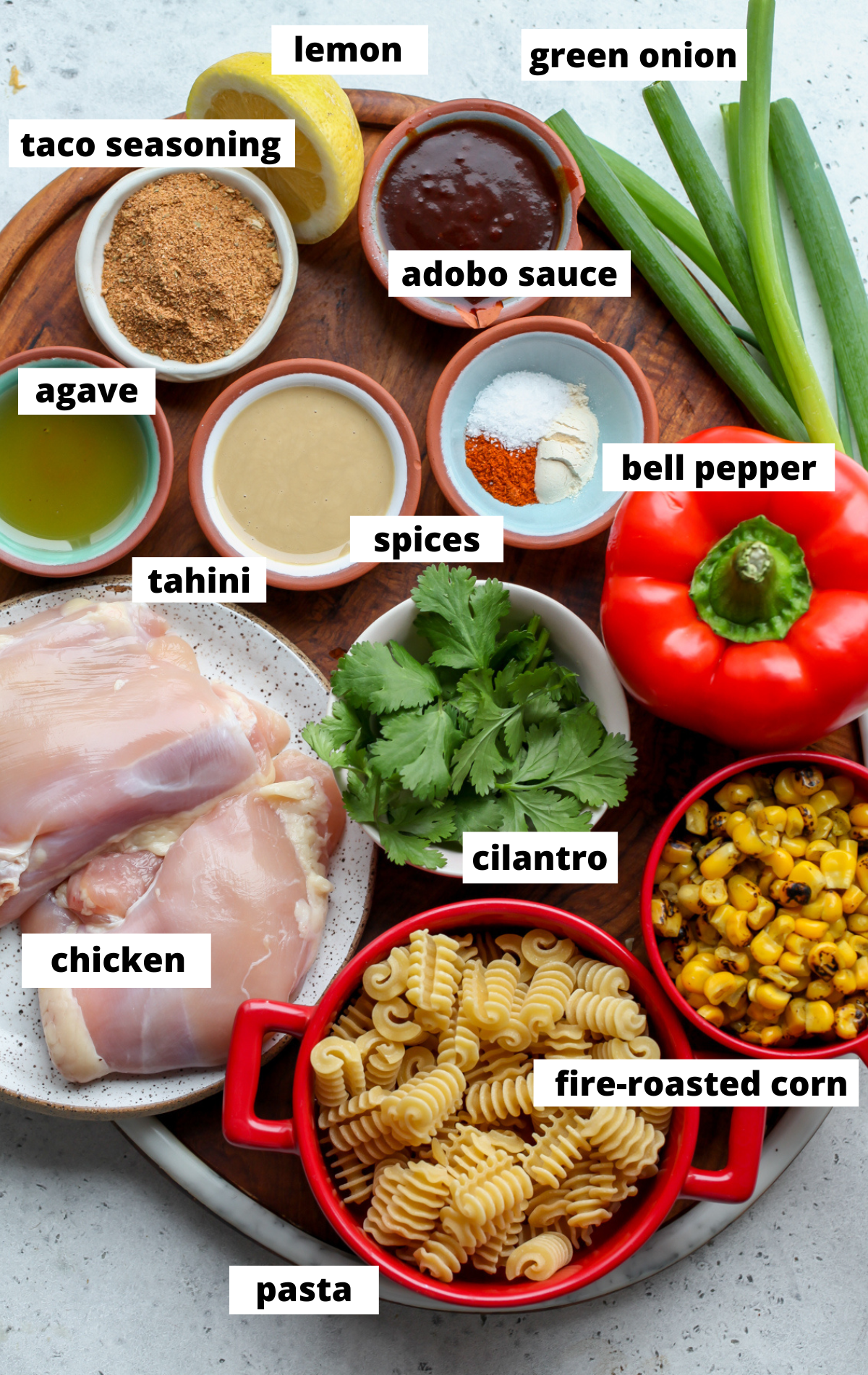 Recipe ingredients arranged on a wooden tray in separate bowls with labels.