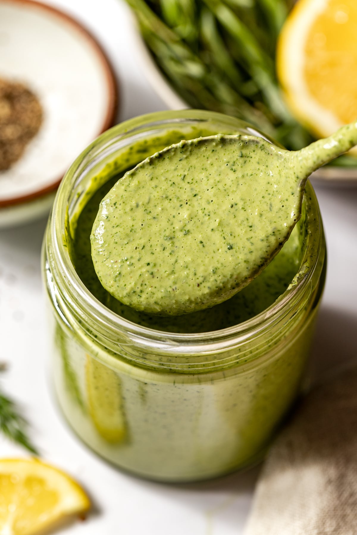 A spoon showing a serving of green goddess tahini dressing.