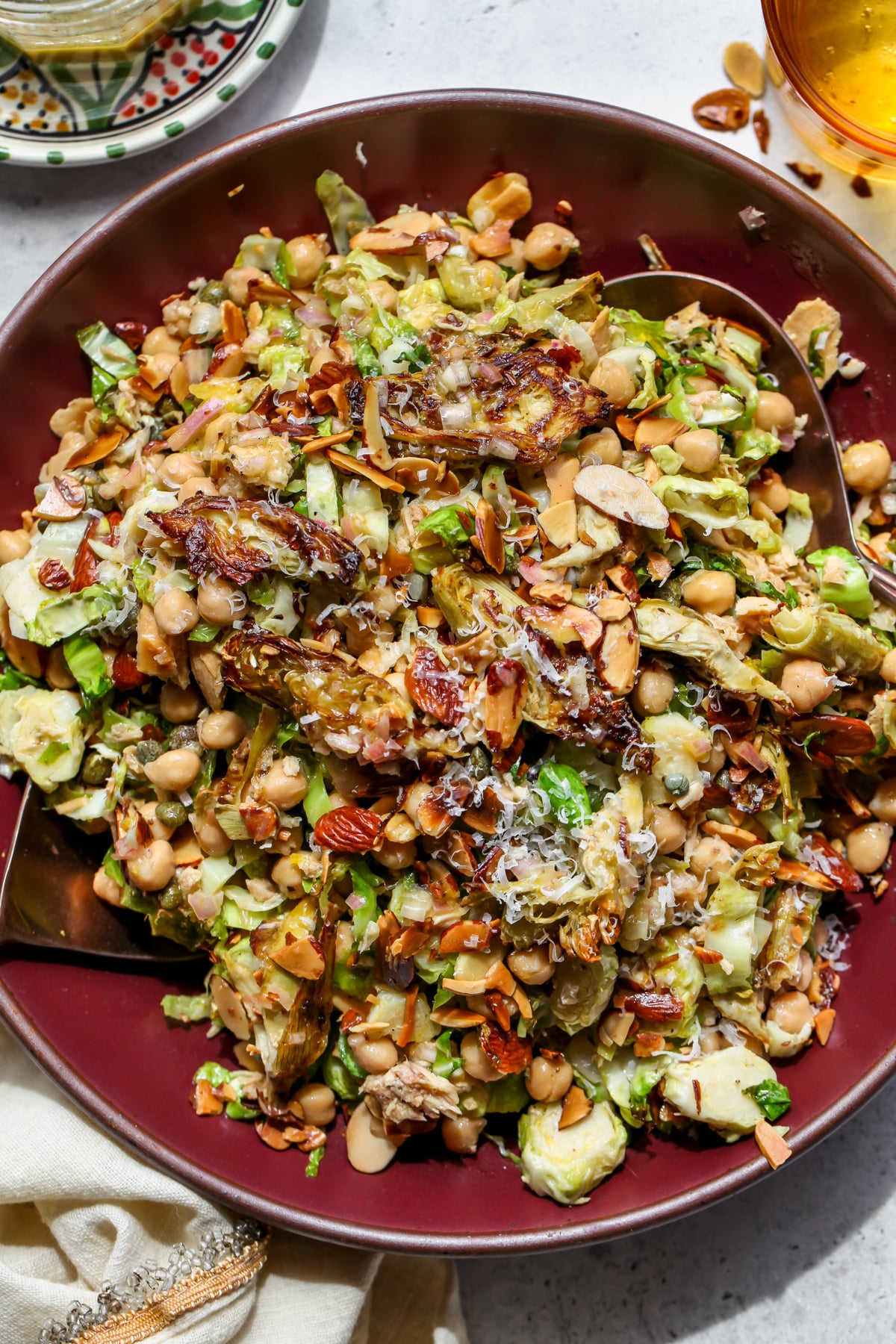 Roasted artichoke salad with lemon shallot dressing styled in a wide rimmed maroon serving bowl.
