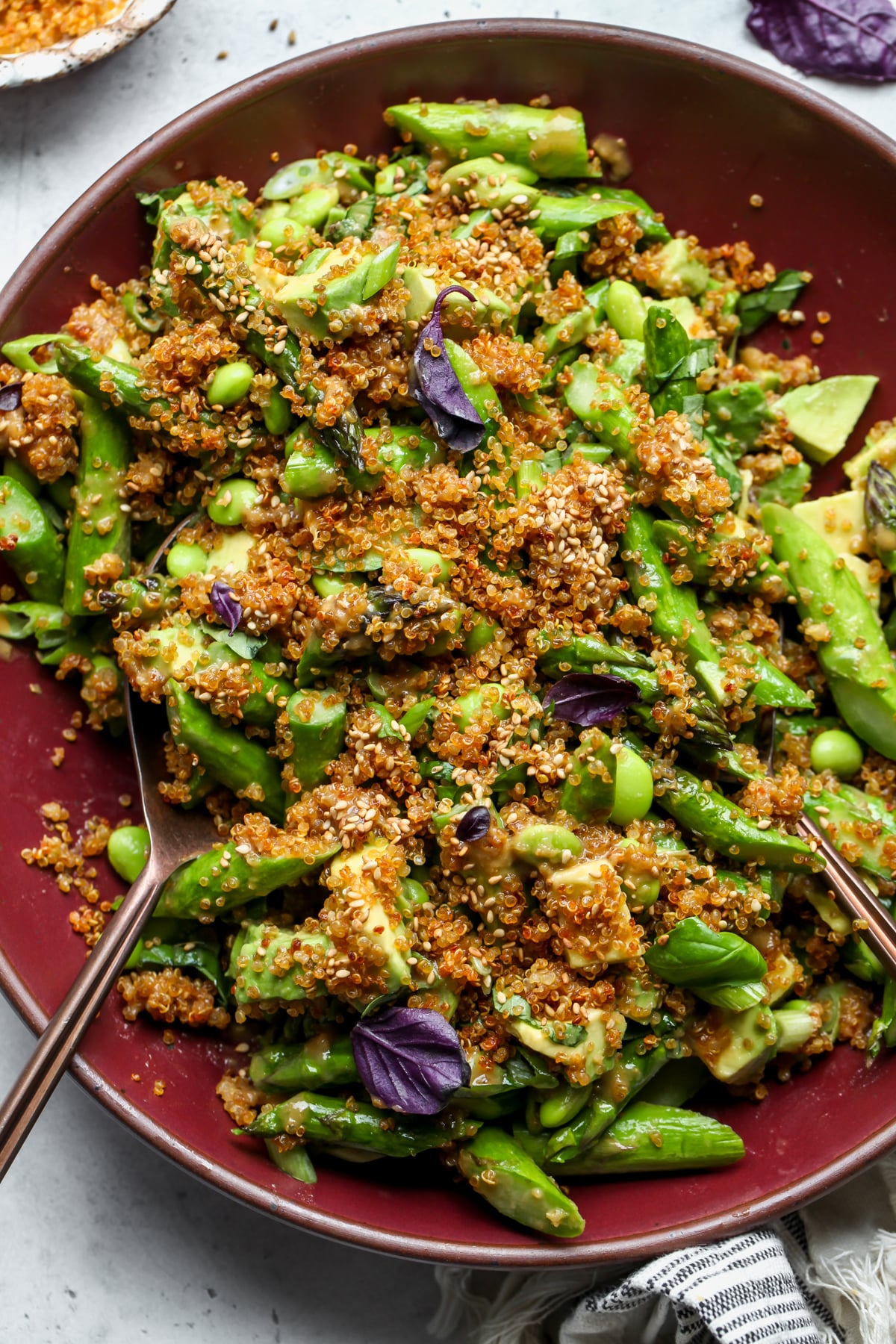 Crispy Quinoa Salad with asparagus and basil styled in a maroon serving bowl.