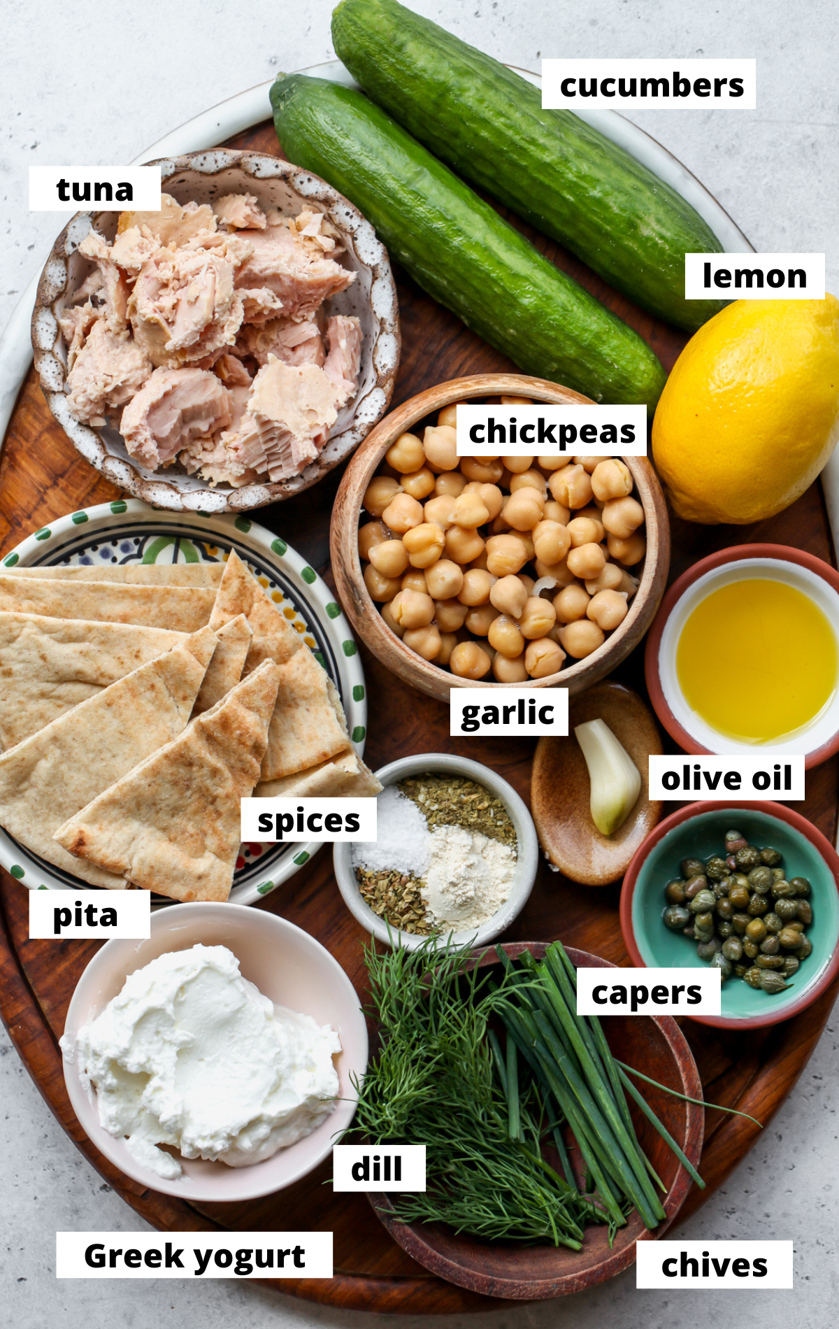 Recipe ingredients in separate bowls arranged on a wooden platter with labels.