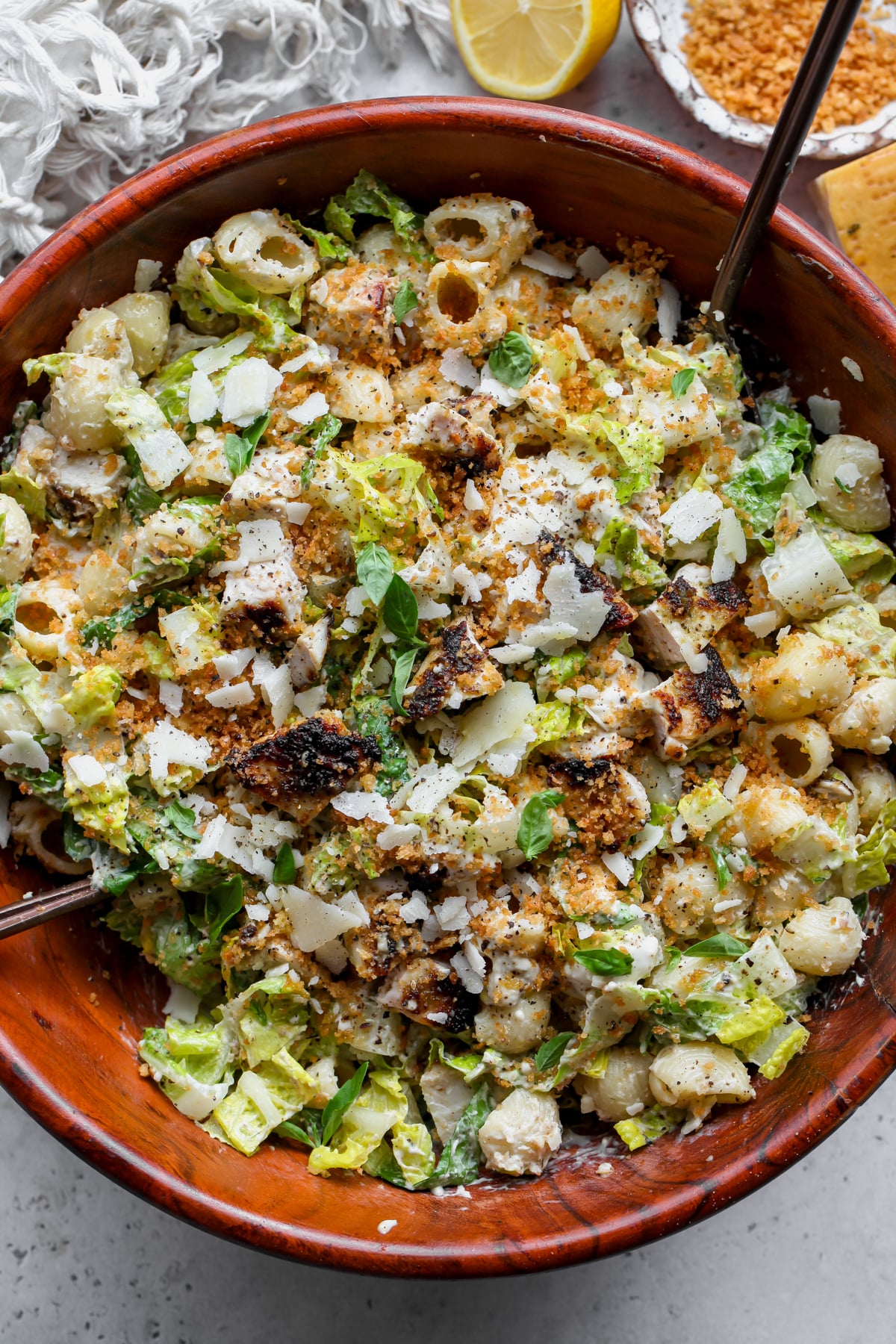Pesto Caesar Pasta Salad styled in a large wooden bowl topped with panko and Parmesan.