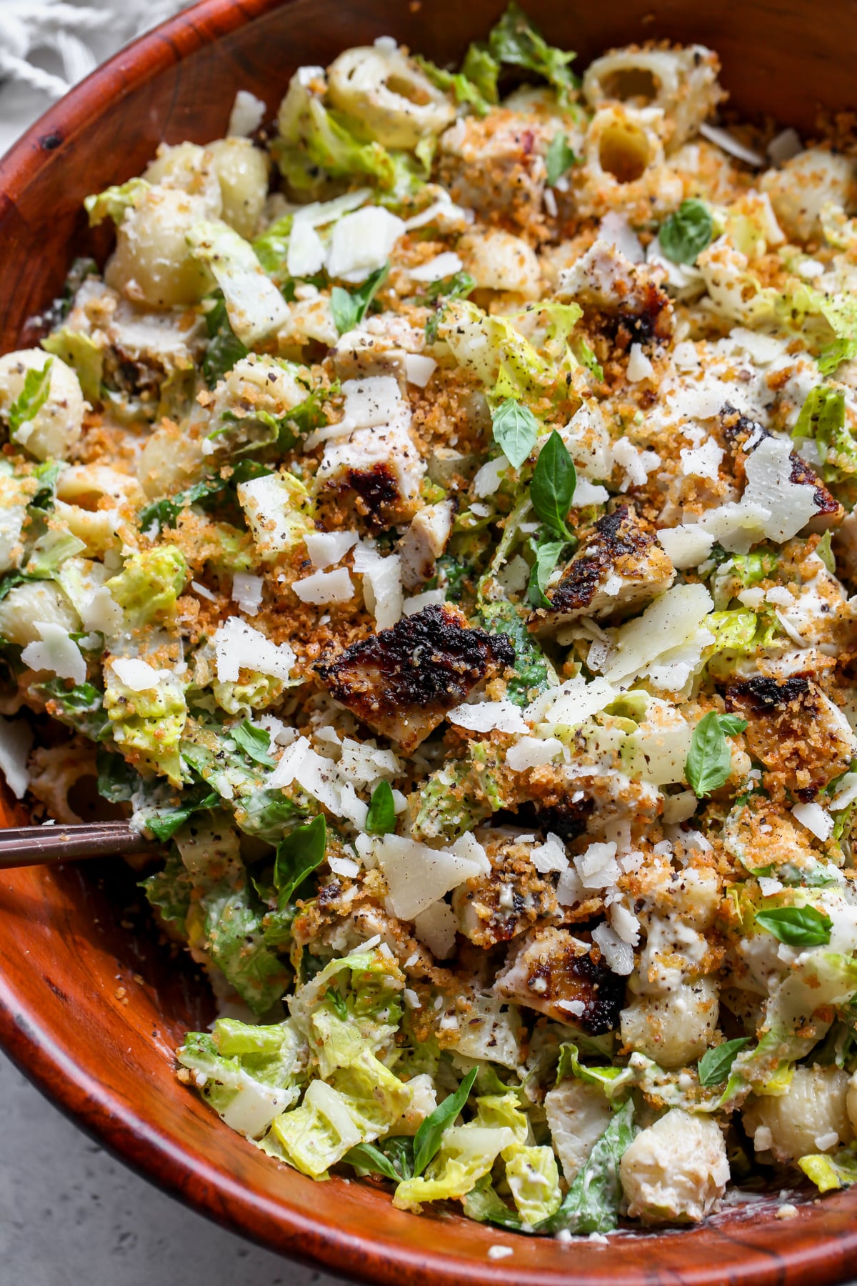 Pesto Caesar pasta salad styled in a large wooden serving bowl.