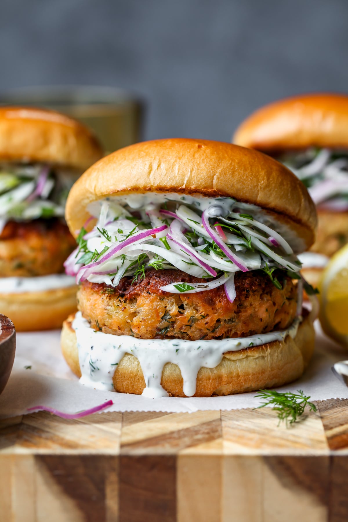 Salmon burgers arranged on a wooden cutting board.