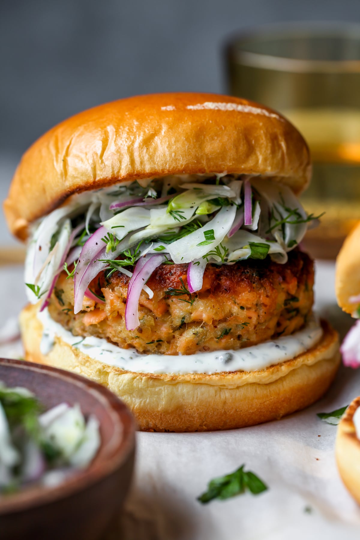 Salmon burger styled on a board topped with fennel slaw and lemon-caper yogurt.