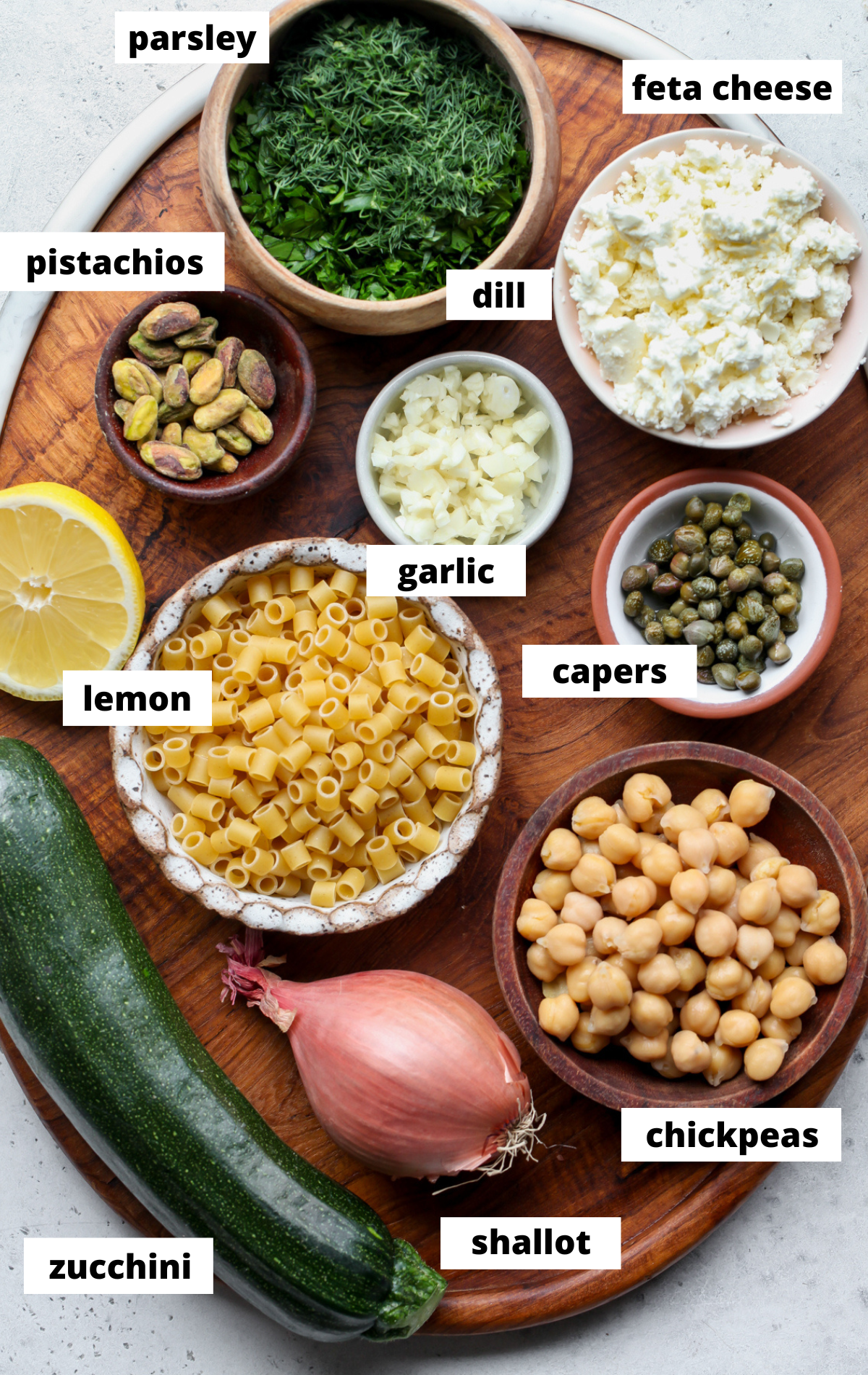 Recipe ingredients in separate bowls arranged on a wooden platter with labels.