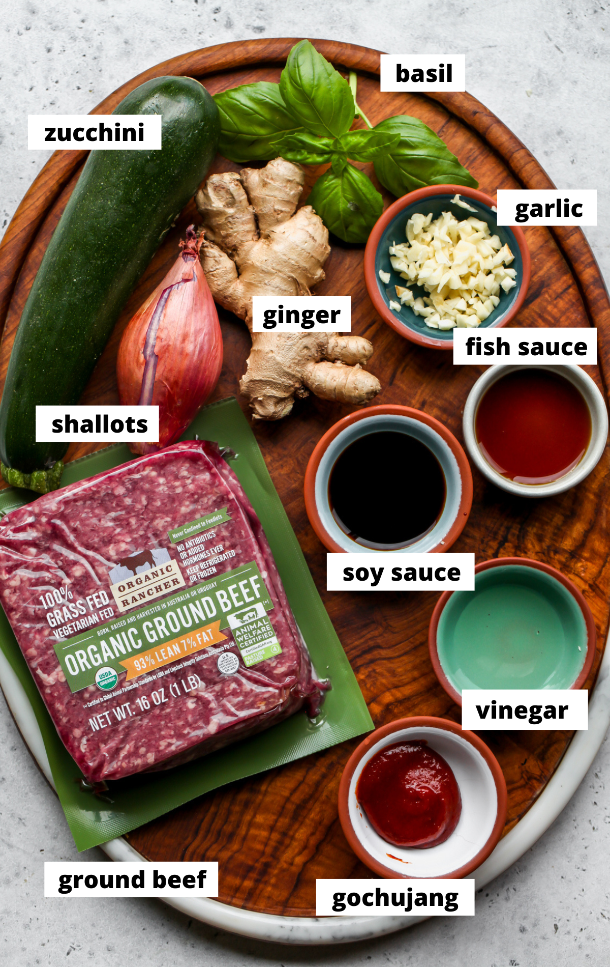 Recipe ingredients in separate bowls arranged on a wooden platter with labels.