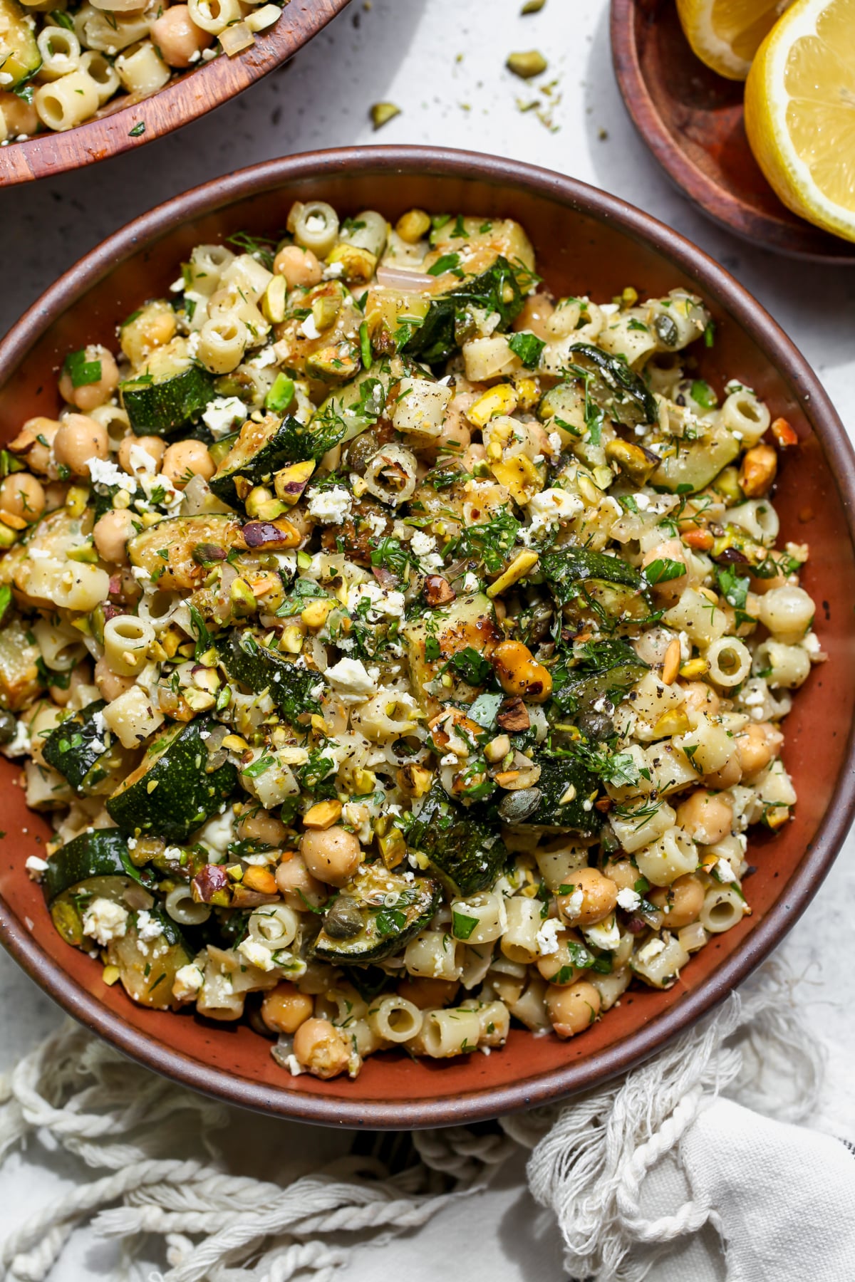 Warm Zucchini and Feta Salad styled in a maroon bowl topped with fresh herbs.