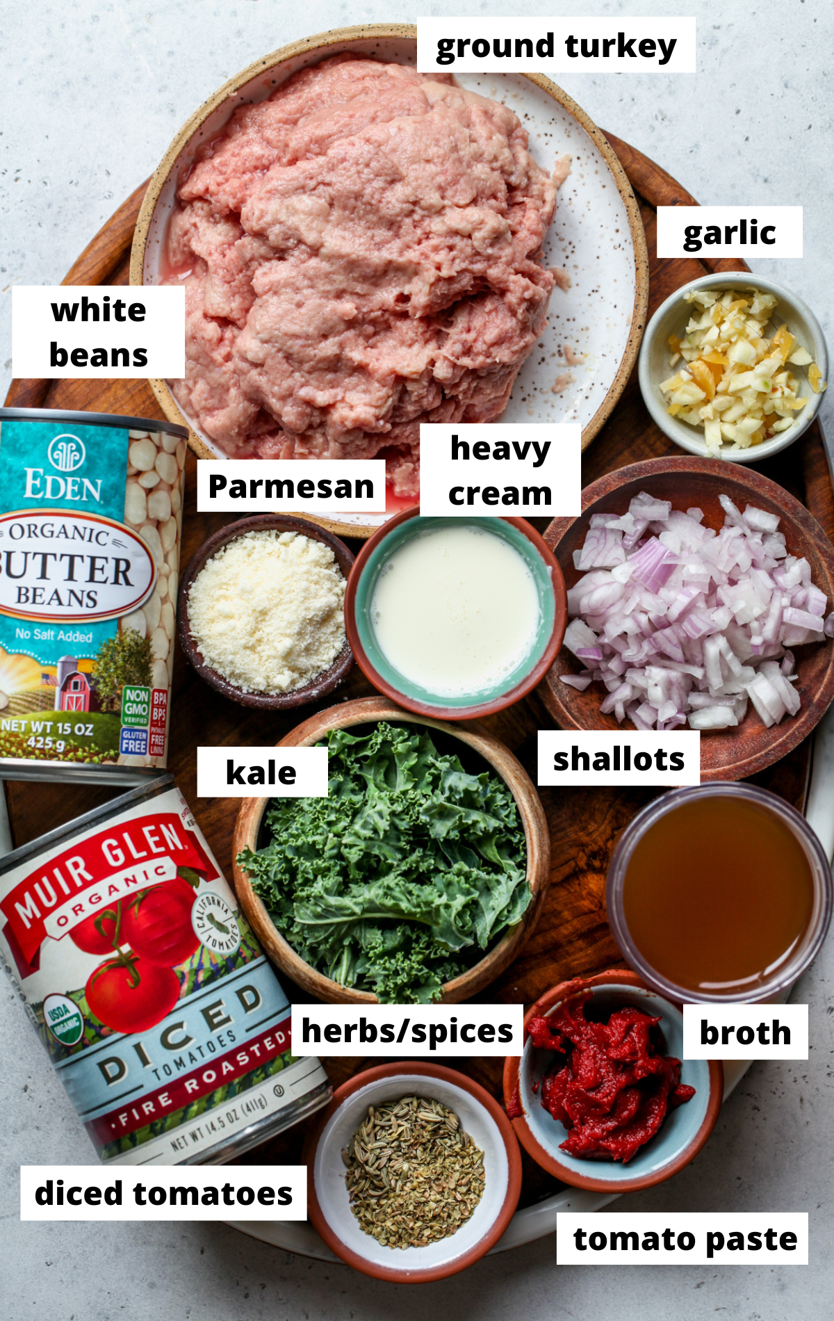 Recipe ingredients in separate bowls arranged on a wooden platter with labels.