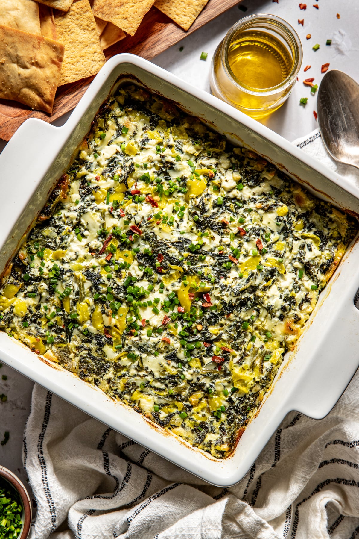 Spinach and pepperoncini baked feta dip in a white square baking dish after baking.
