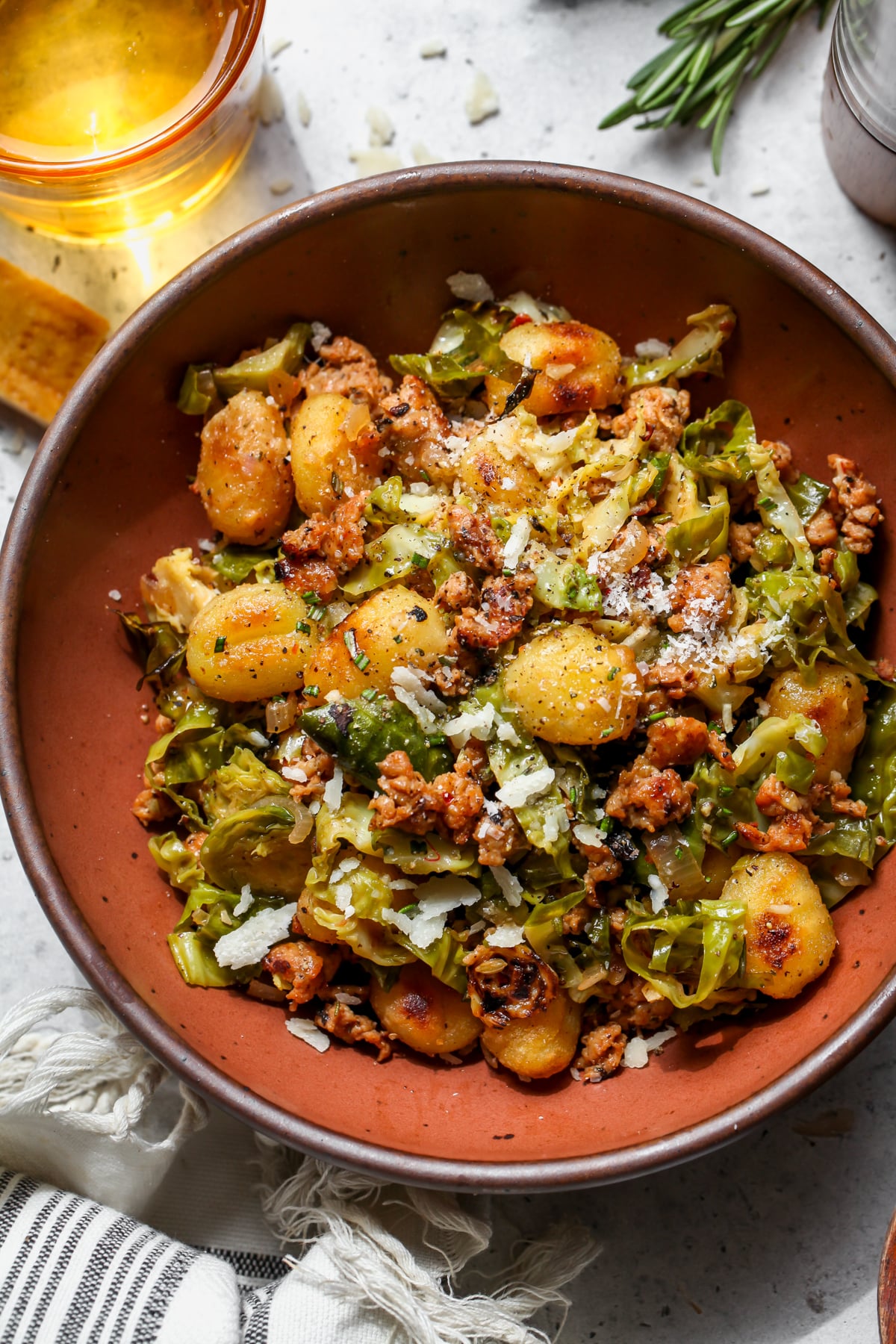 Maroon bowl filled with crispy gnocchi, sausage, and brussels sprouts.