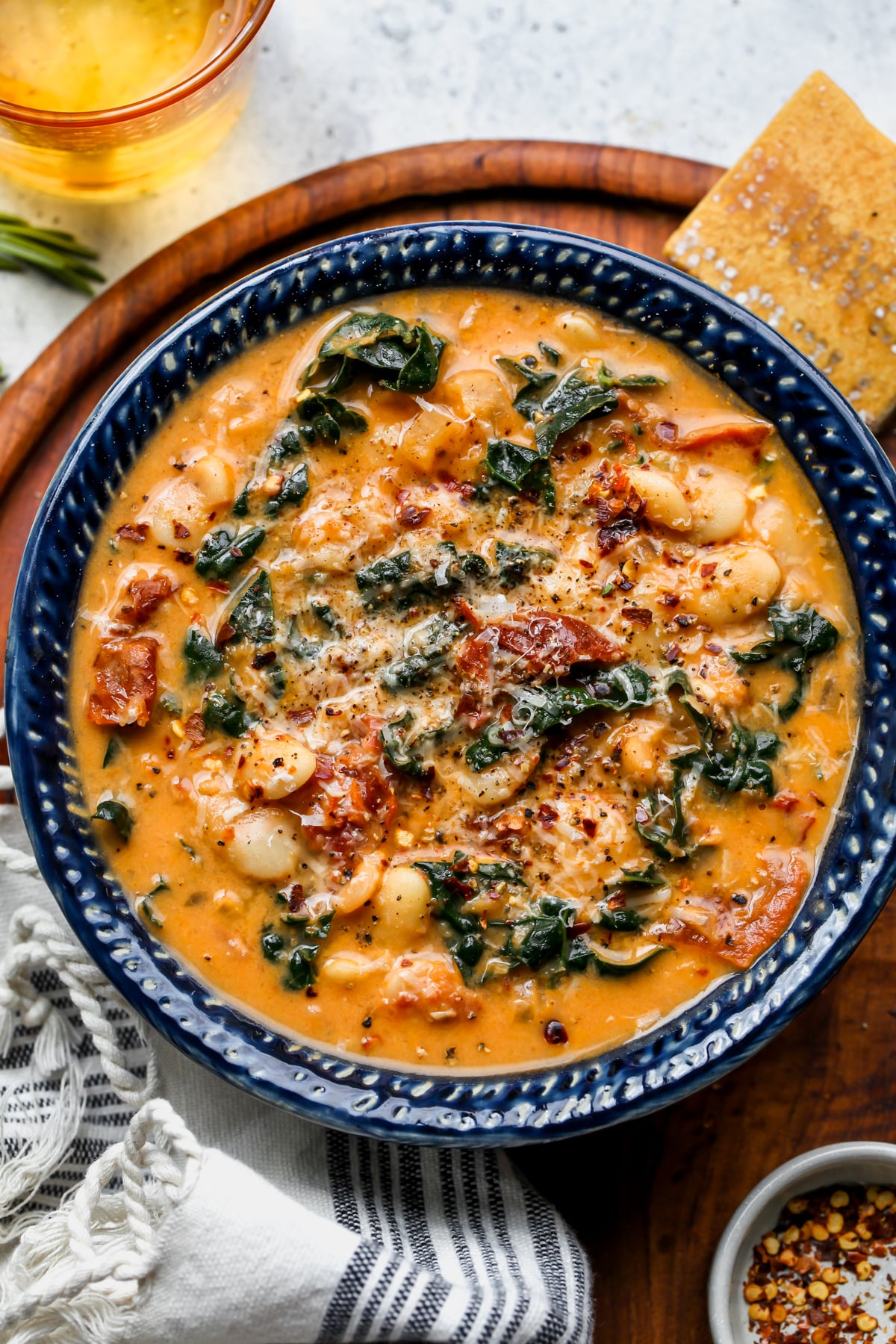 Tuscan Butter Bean Soup styled in a blue bowl on a wooden board.