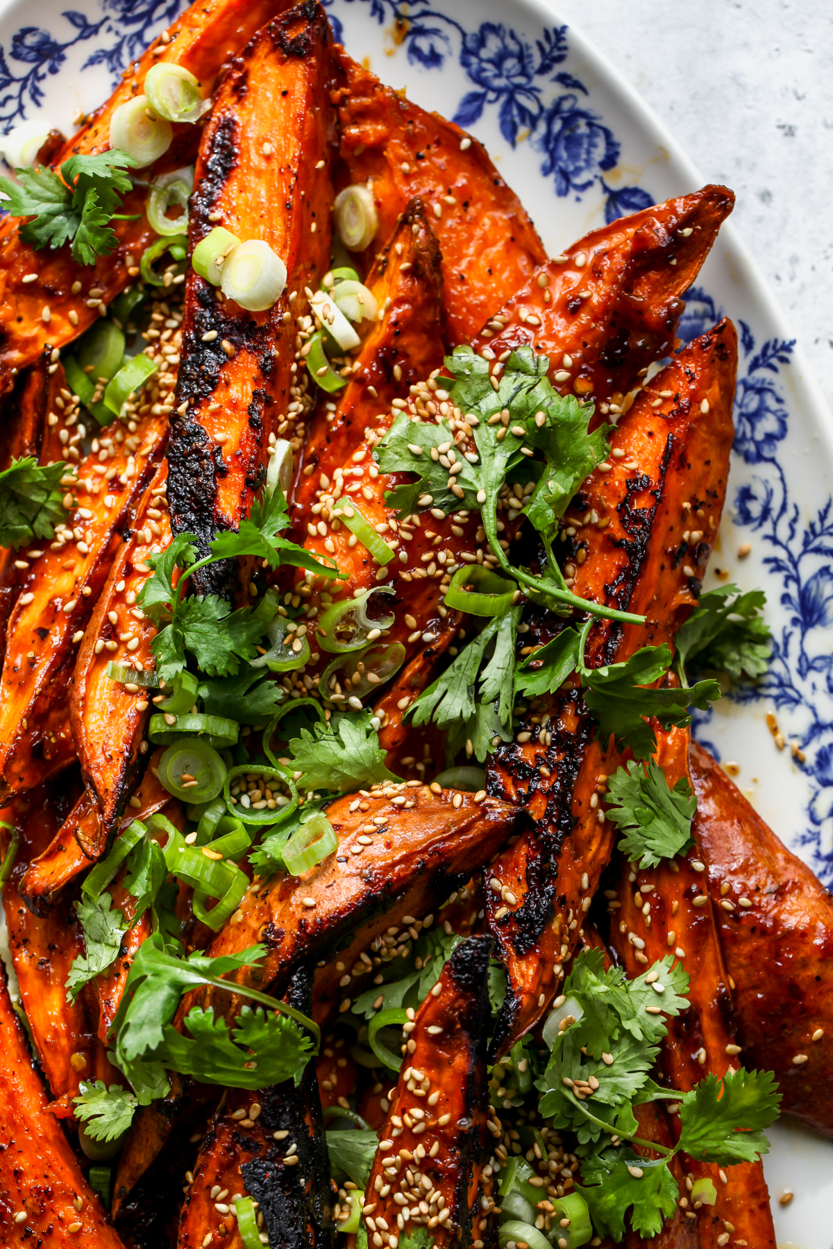 Miso-Maple Glazed Sweet Potato wedges styled on a blue and white floral platter.