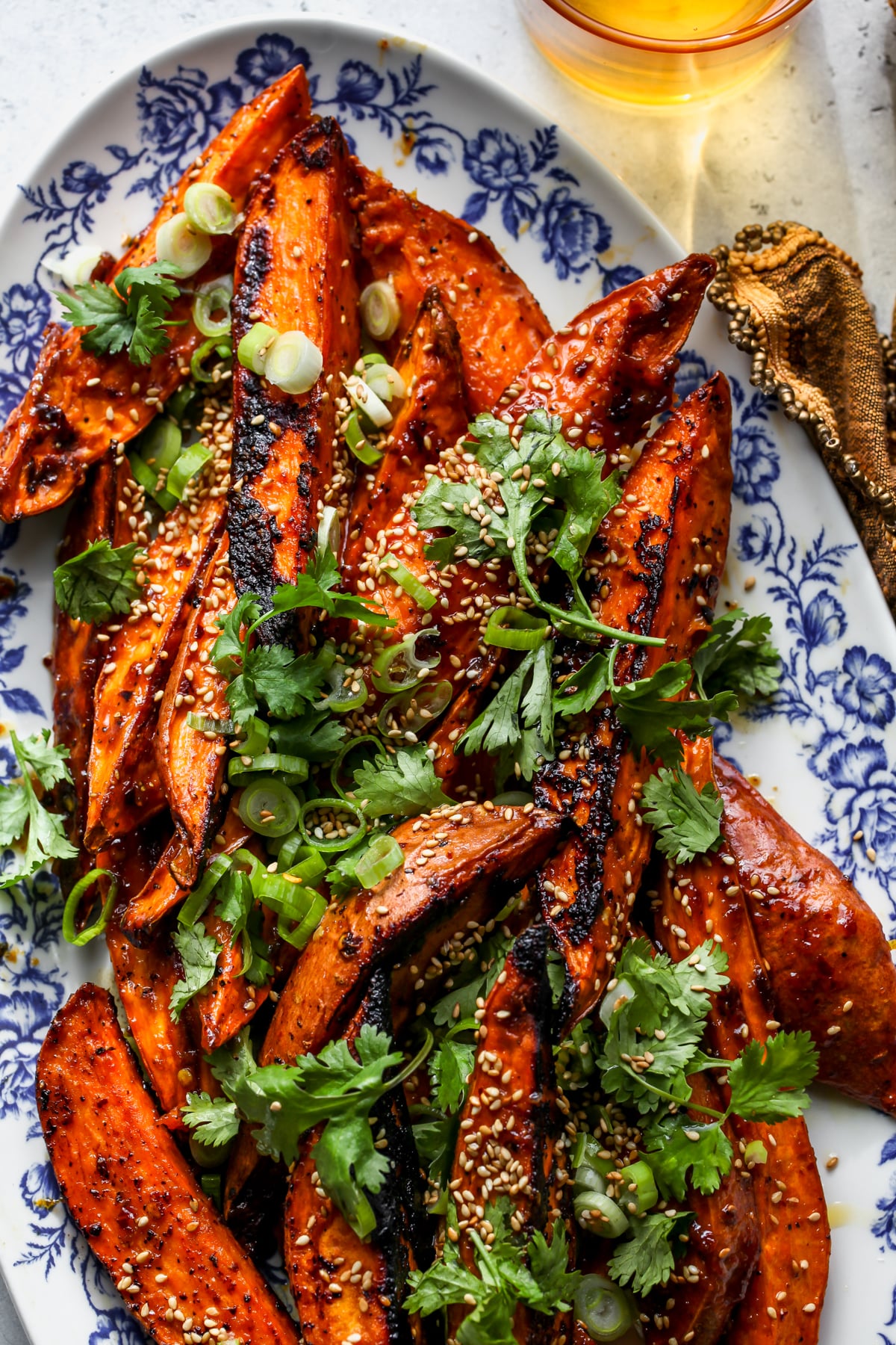 Sweet potato wedges arranged on a platter topped with herbs and sesame seeds.