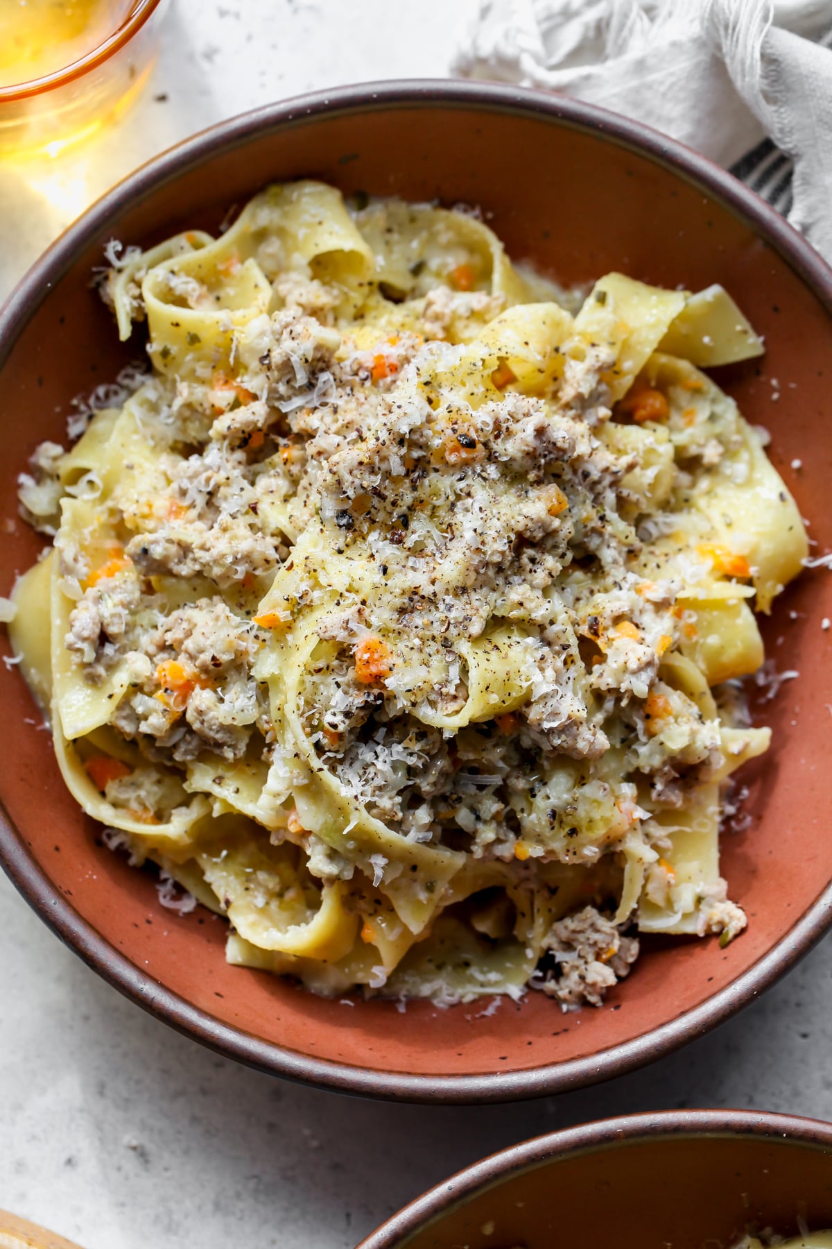 White Bolognese (Ragù Bianco) with pappardelle styled in a maroon bowl.