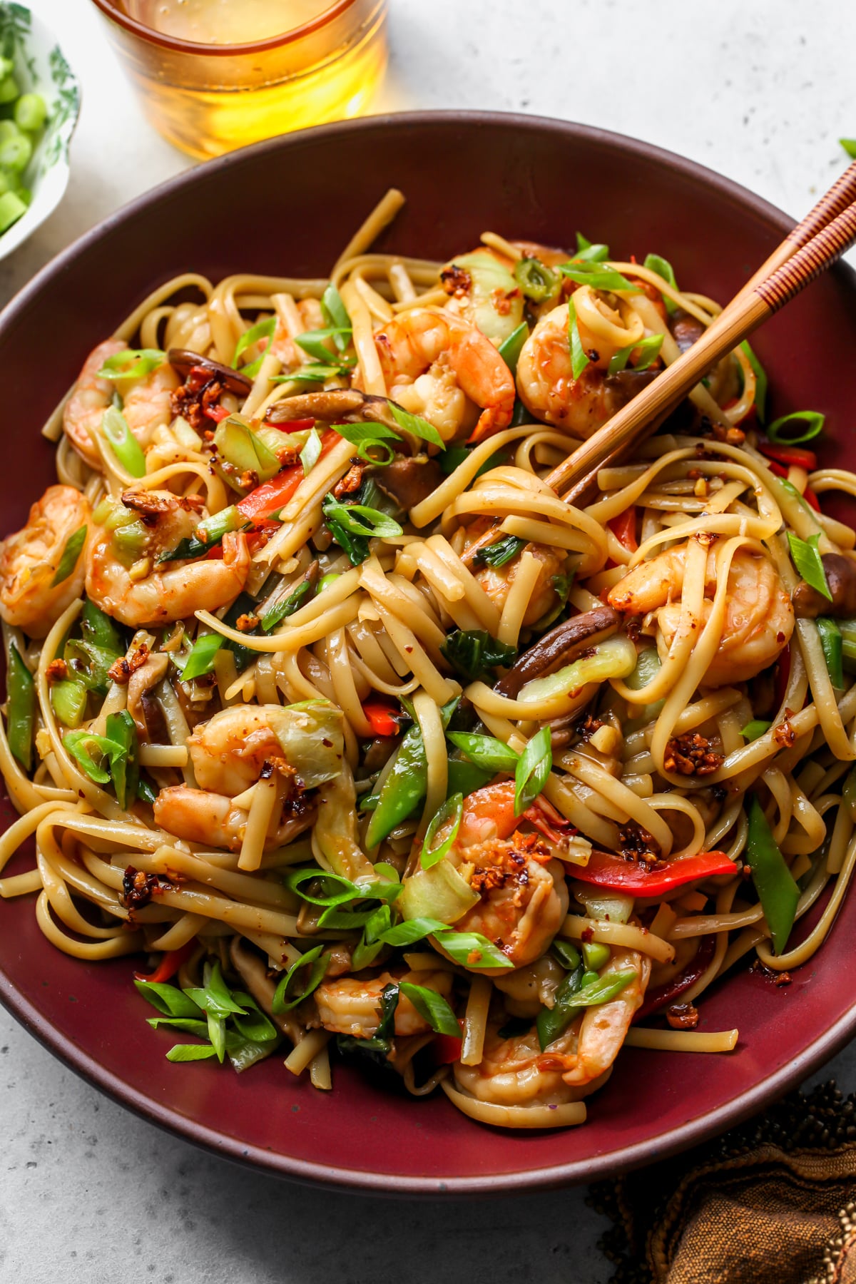 Shrimp Lo Mein being twirled with chopsticks in a large maroon bowl.