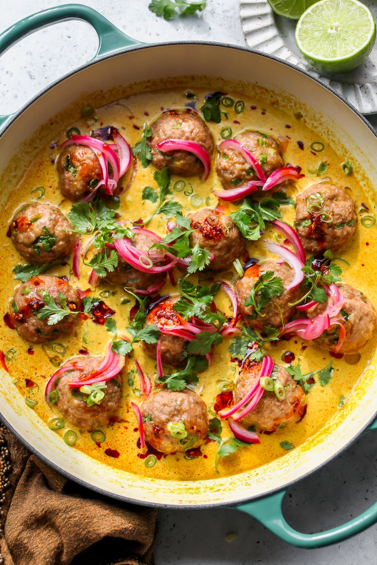 Creamy Coconut Chicken Satay Meatballs styled in a sauté pan on a gray surface.