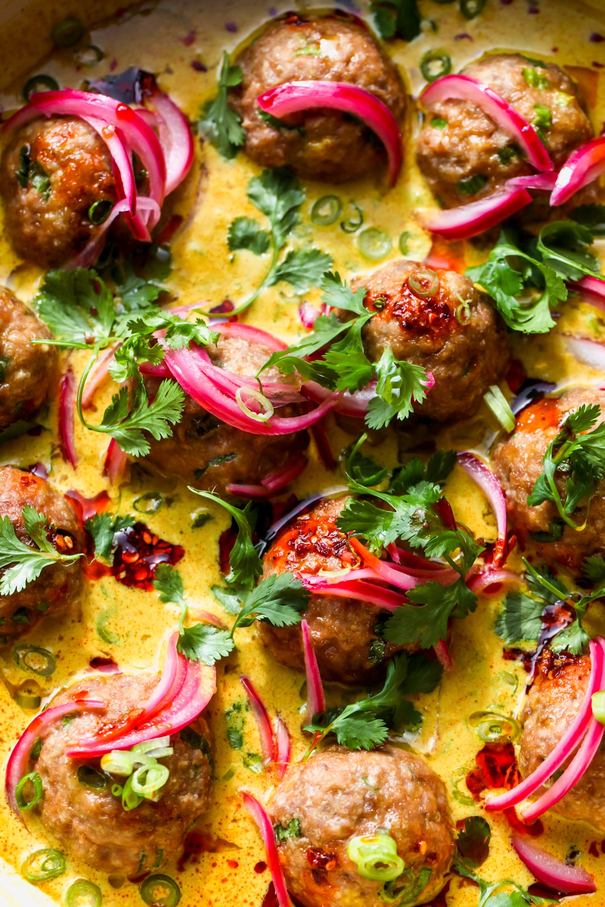 Chicken satay meatballs in coconut-peanut sauce topped with cilantro and pickled red onion.