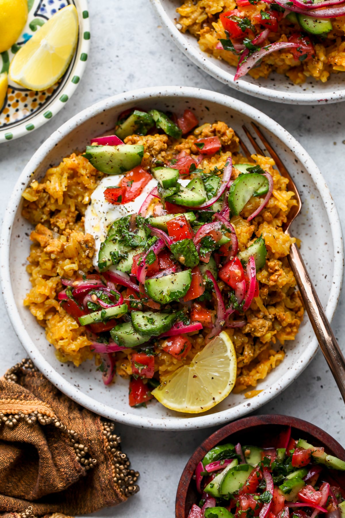 Golden Ground Turkey and Rice in a white bowl topped with yogurt and cucumber salad.