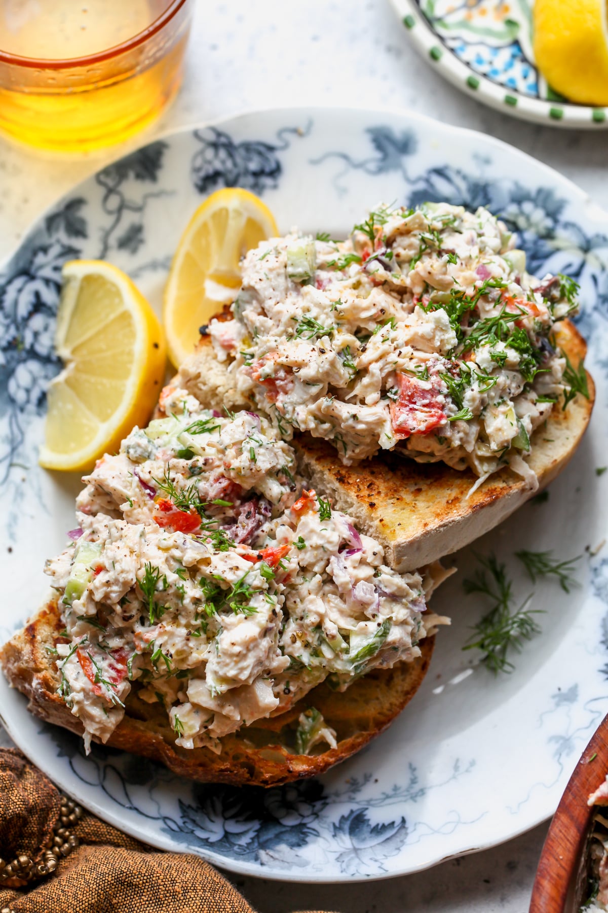 Greek Chicken Salad scooped onto two slices of toasted sourdough bread on a blue and white floral plate.