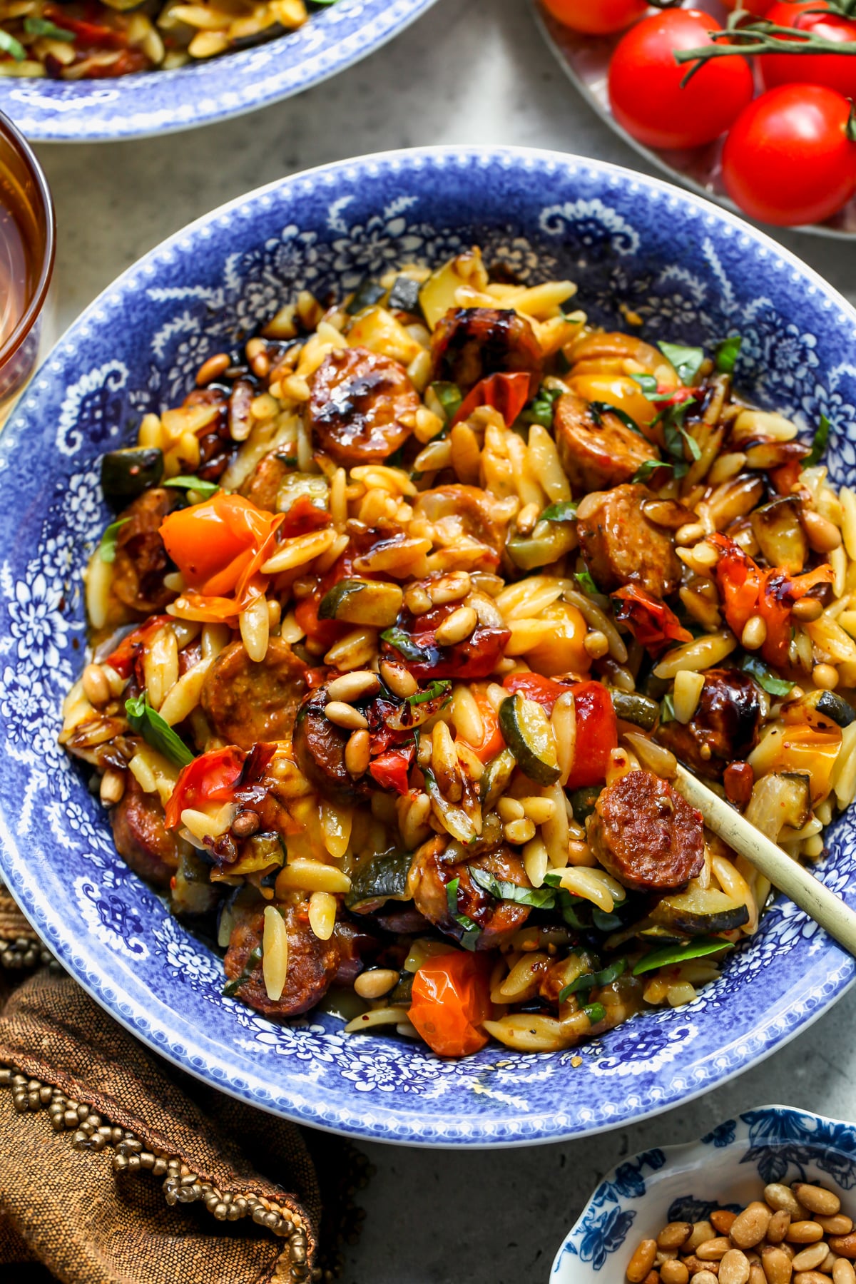 Chicken sausage orzo in a blue and white floral pasta bowl with a spoon resting on the right side.