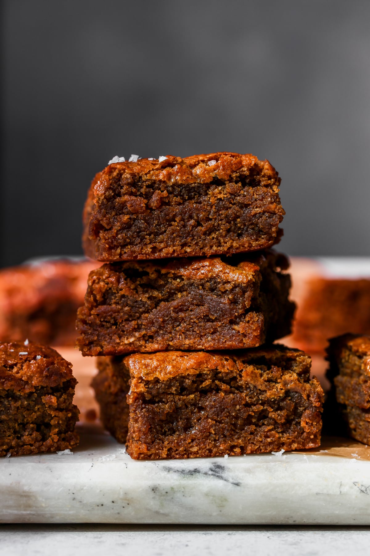 Three Brown Butter Pumpkin Tahini Bars stacked on top of each other on a white cutting board.